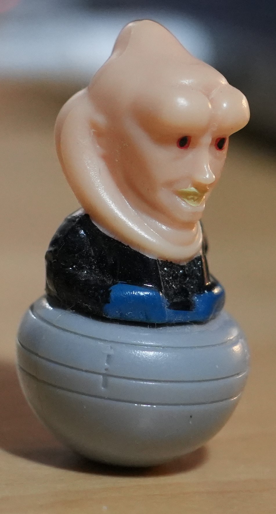 An ugly plastic figurine, depicting the bust and head of Bib Fortuna, with a ridged grey sphere instead of his legs.