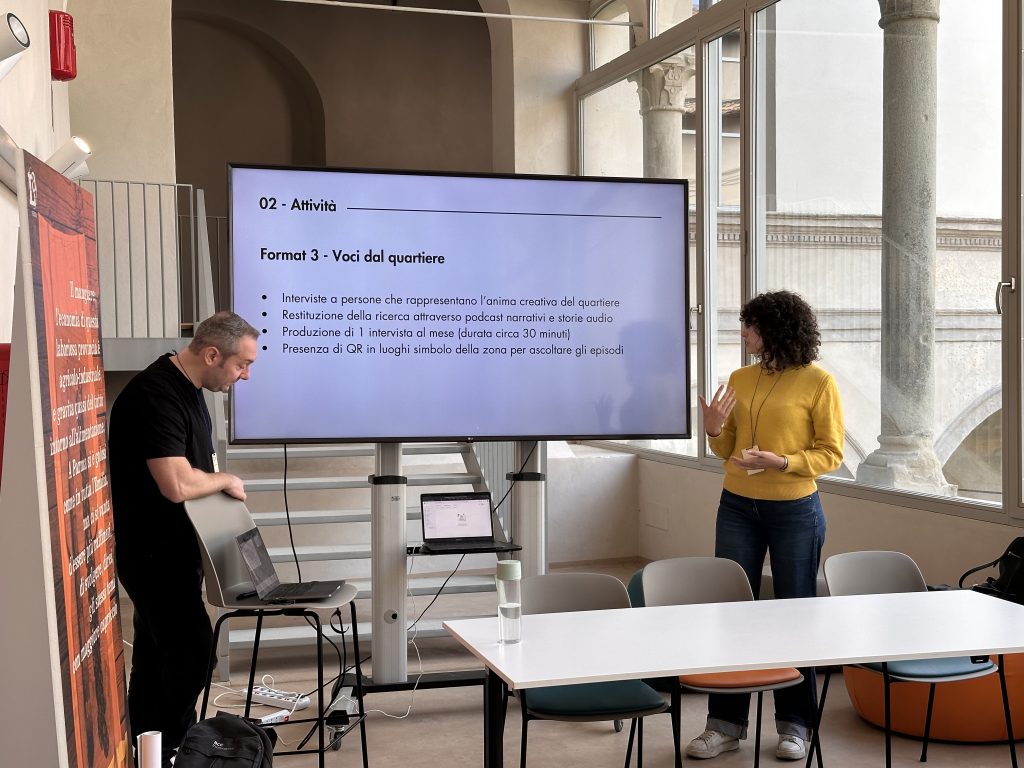 Benedetta presenting while Ruggero operates the slide show